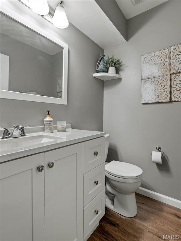 447 Omar Ct, Saint Peters, MO 63376 - half bathroom featuring wood finished floors, toilet, vanity, and baseboards