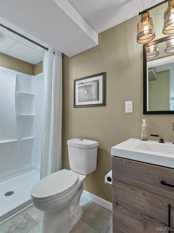447 Omar Ct, Saint Peters, MO 63376 - full bath with tile patterned flooring, toilet, a stall shower, baseboards, and vanity