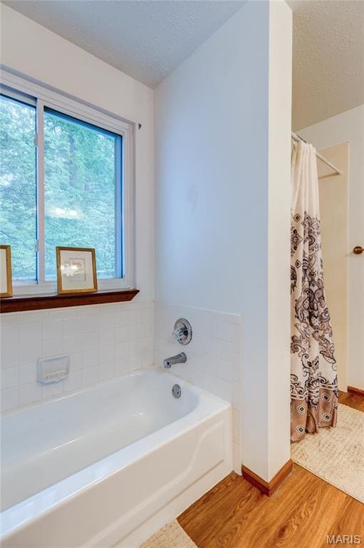 1101 Nathaniel Ct, Hazelwood, MO 63042 - bathroom with wood finished floors, a bath, curtained shower, baseboards, and a textured ceiling