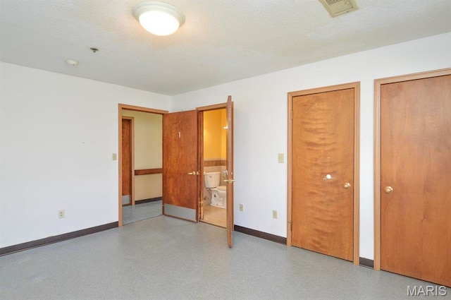 620 N Main St, Hoyleton, IL 62803 - unfurnished bedroom featuring baseboards, two closets, ensuite bath, and a textured ceiling