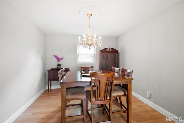 dining area featuring a chandelier, light wood-type flooring, and baseboards