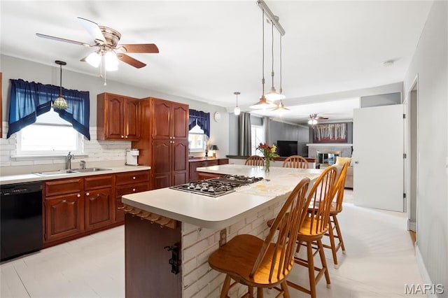 kitchen featuring ceiling fan, stainless steel gas stovetop, a sink, dishwasher, and light countertops