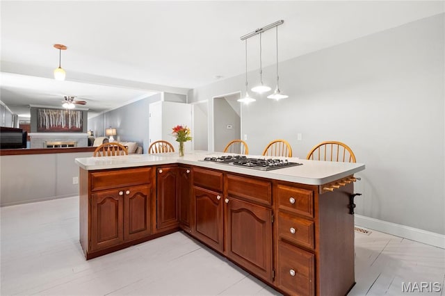 kitchen with stainless steel gas stovetop, pendant lighting, light countertops, and a ceiling fan