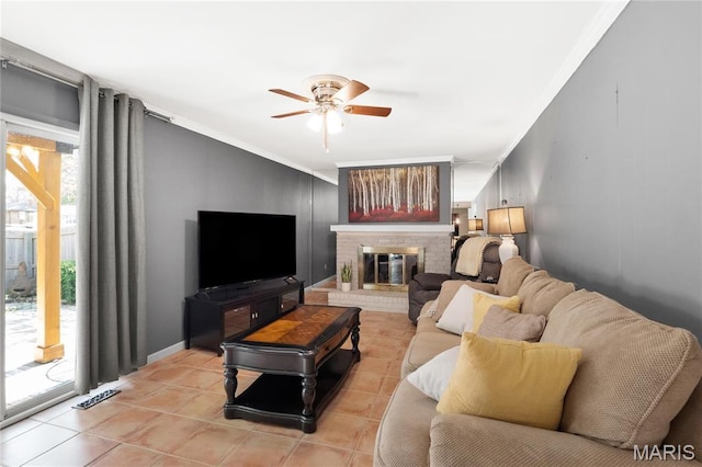 living area featuring a ceiling fan, light tile patterned flooring, ornamental molding, and a brick fireplace