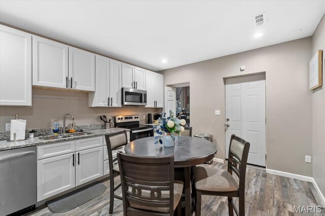 1428 Mallinckrodt, Saint Louis, MO 63107 - kitchen featuring stainless steel appliances, a sink, white cabinets, light wood-style floors, and baseboards