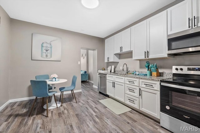 1428 Mallinckrodt, Saint Louis, MO 63107 - kitchen featuring stainless steel appliances, a sink, baseboards, light wood-style flooring, and white cabinets