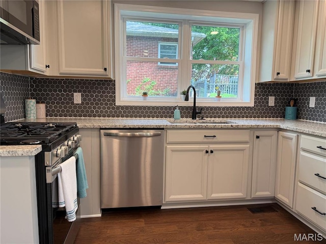 409 Oak St, East Alton, IL 62024 - kitchen with stainless steel appliances, a sink, dark wood-style floors, backsplash, and white cabinets