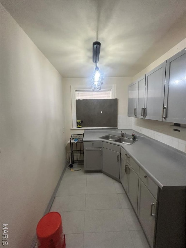 916 Eastgate Ave, Saint Louis, MO 63130 - kitchen with a sink, gray cabinets, decorative backsplash, light tile patterned floors, and baseboards
