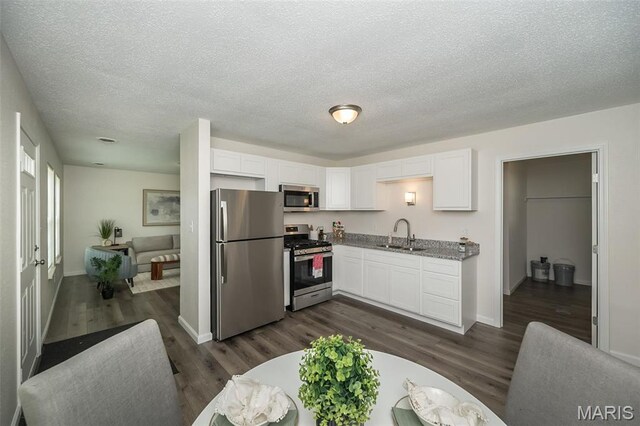 1331 Belrue Ave, Saint Louis, MO 63133 - kitchen with stainless steel appliances, a sink, white cabinetry, dark wood-type flooring, and a textured ceiling
