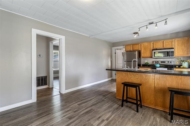 314 S Carleton St, Farmington, MO 63640 - kitchen featuring appliances with stainless steel finishes, dark wood-style floors, dark countertops, a kitchen breakfast bar, and baseboards