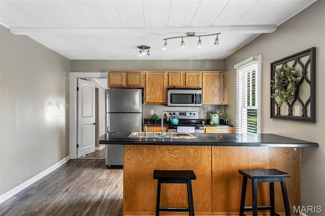 314 S Carleton St, Farmington, MO 63640 - kitchen featuring appliances with stainless steel finishes, dark wood-style flooring, dark countertops, and a kitchen breakfast bar