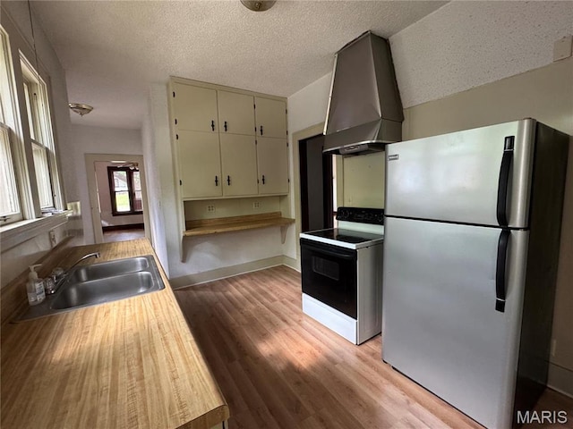 813 Main St, Poplar Bluff, MO 63901 - kitchen with freestanding refrigerator, electric stove, a sink, wall chimney range hood, and light wood finished floors