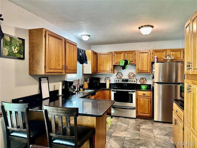 1725 Spruce Hill Dr, Belleville, IL 62221 - kitchen with appliances with stainless steel finishes, a sink, a peninsula, dark countertops, and stone finish flooring