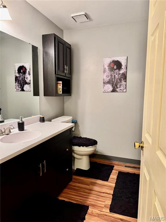 1725 Spruce Hill Dr, Belleville, IL 62221 - bathroom with wood finished floors, vanity, toilet, and baseboards