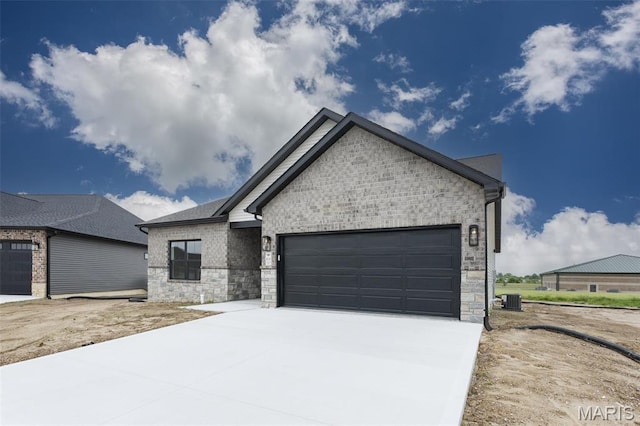 view of front of house with central AC, an attached garage, concrete driveway, and stone siding