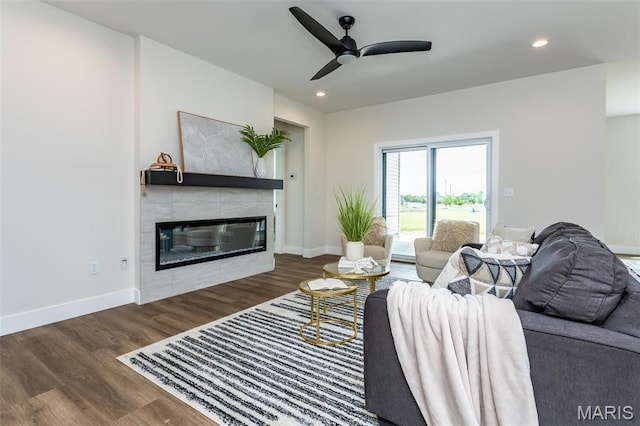 living area with wood finished floors, a tile fireplace, a ceiling fan, recessed lighting, and baseboards