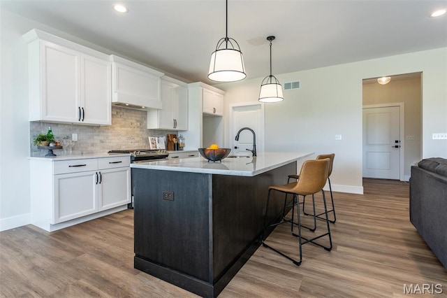 kitchen with gas stove, white cabinetry, baseboards, backsplash, and recessed lighting
