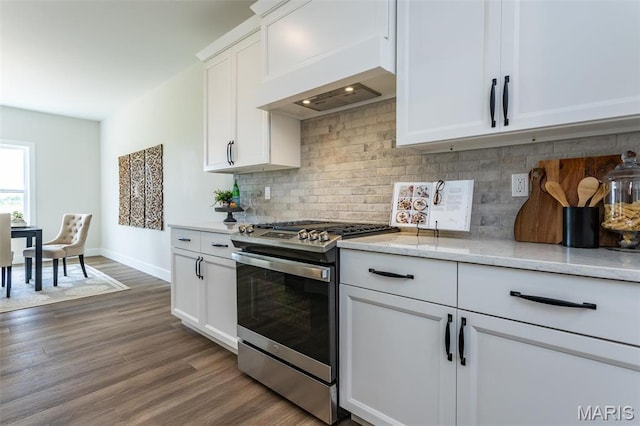 kitchen featuring stainless steel gas stove, dark wood-style flooring, white cabinets, backsplash, and baseboards