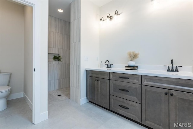 full bathroom featuring toilet, a walk in shower, a sink, and baseboards