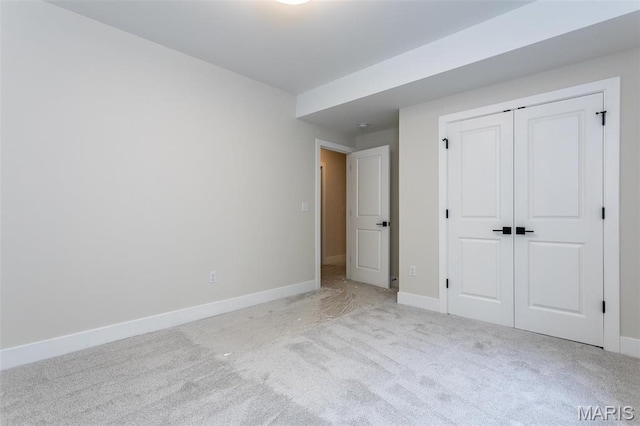 unfurnished bedroom featuring carpet flooring, baseboards, and a closet