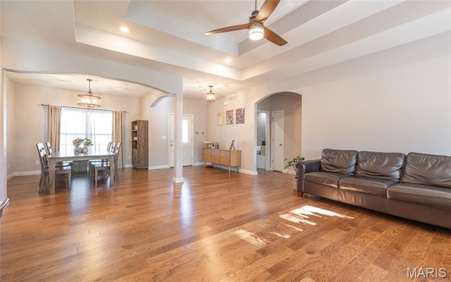 1347 Thomas Dr, Rolla, MO 65401 - living room with arched walkways, ceiling fan, light wood-style floors, a tray ceiling, and baseboards