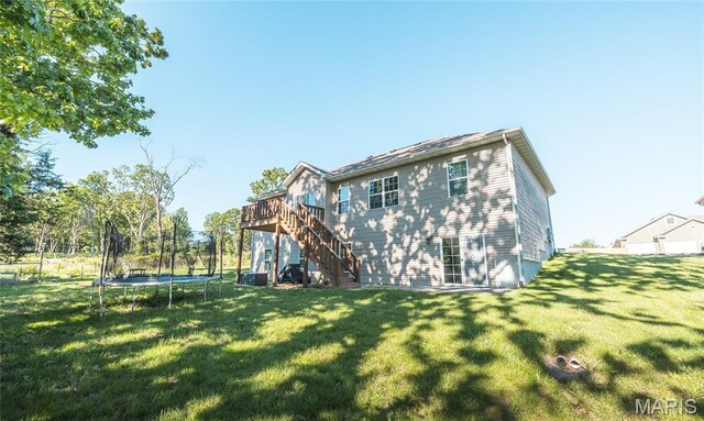 1347 Thomas Dr, Rolla, MO 65401 - rear view of house featuring a trampoline, stairs, a wooden deck, and a lawn