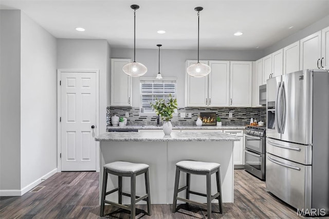 153 Stella Cherry Way, Wildwood, MO 63040 - kitchen with appliances with stainless steel finishes, decorative backsplash, white cabinets, a breakfast bar, and dark wood-type flooring