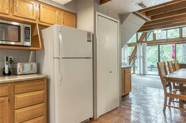 1235 Powderhorn Dr, Innsbrook, MO 63390 - kitchen featuring freestanding refrigerator, stainless steel microwave, light countertops, and vaulted ceiling