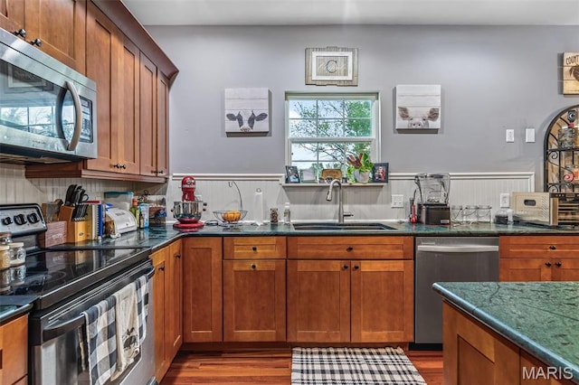 802 Hager Rd, Farmington, MO 63640 - kitchen featuring stainless steel appliances, a sink, wood finished floors, dark stone counters, and brown cabinetry