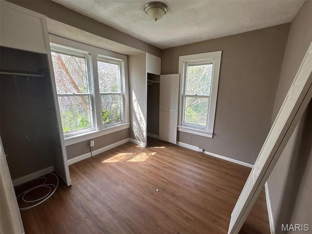 339 Midridge Dr, Saint Louis, MO 63137 - unfurnished bedroom featuring baseboards, wood finished floors, a textured ceiling, and multiple windows