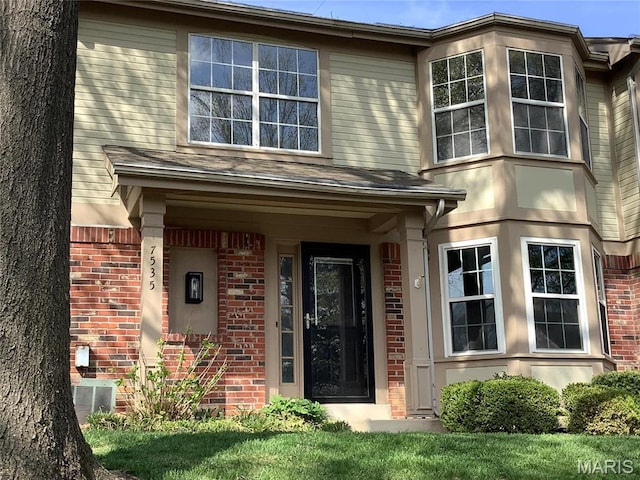 doorway to property featuring brick siding and central AC unit