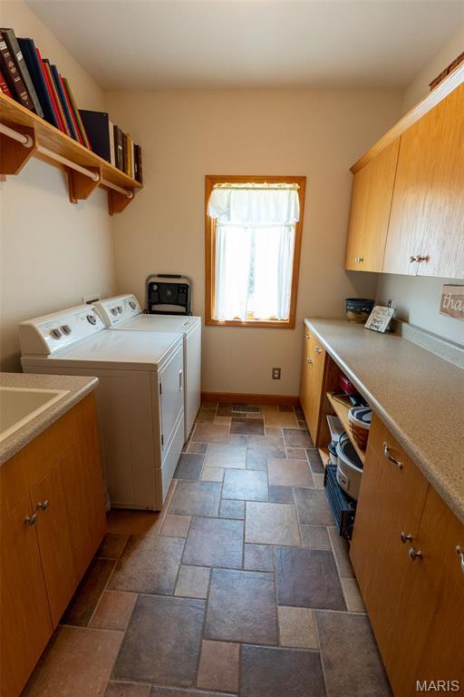 14035 County Road 4110, Rolla, MO 65401 - clothes washing area featuring washing machine and clothes dryer, cabinet space, stone tile floors, and baseboards