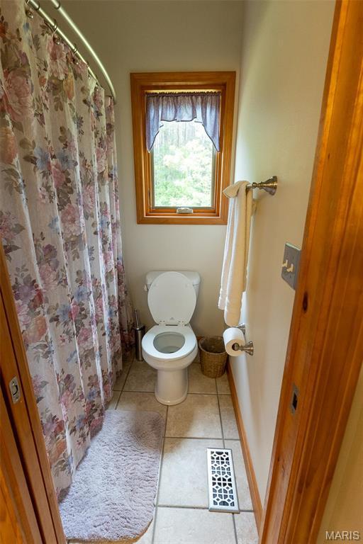 14035 County Road 4110, Rolla, MO 65401 - bathroom with tile patterned flooring, toilet, a shower with curtain, and baseboards