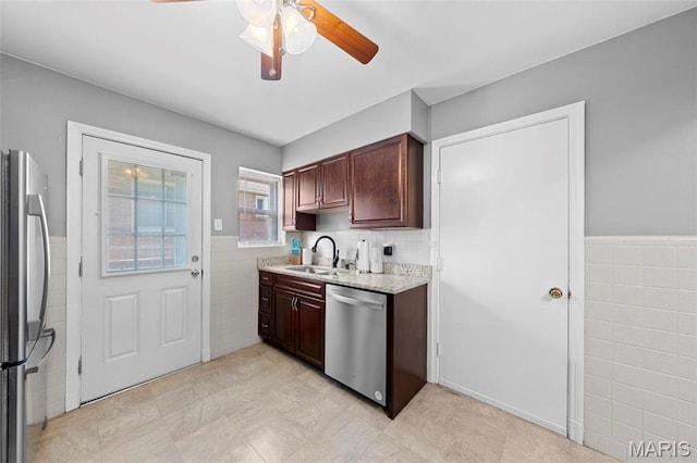 8452 S Laclede Station Rd, Saint Louis, MO 63123 - kitchen with appliances with stainless steel finishes, tile walls, a sink, a ceiling fan, and a wainscoted wall
