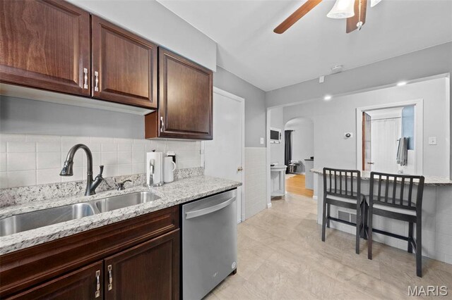 8452 S Laclede Station Rd, Saint Louis, MO 63123 - kitchen featuring stainless steel dishwasher, a sink, arched walkways, a ceiling fan, and light stone counters