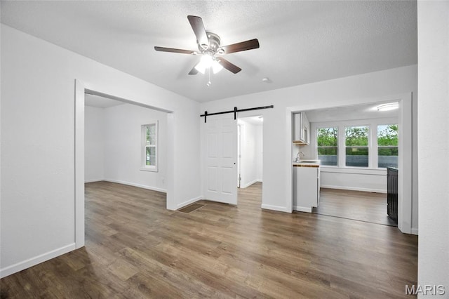 202 N Thomas St, De Soto, MO 63020 - unfurnished living room featuring a barn door, ceiling fan, dark wood-style floors, and baseboards