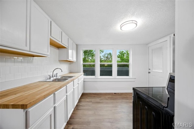 202 N Thomas St, De Soto, MO 63020 - kitchen with electric range, a sink, baseboards, light wood-type flooring, and a textured ceiling