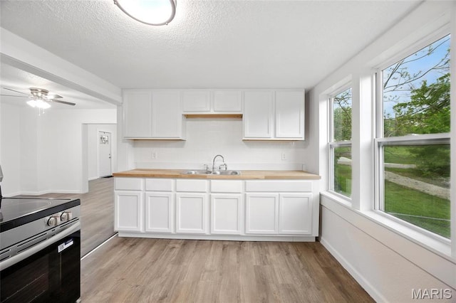 202 N Thomas St, De Soto, MO 63020 - kitchen featuring electric range, wood counters, a sink, light wood-style flooring, and white cabinets