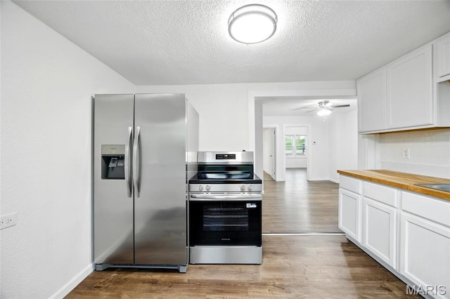 202 N Thomas St, De Soto, MO 63020 - kitchen featuring appliances with stainless steel finishes, wood finished floors, butcher block counters, white cabinets, and a textured ceiling