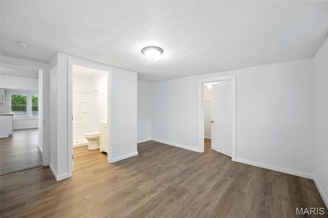 202 N Thomas St, De Soto, MO 63020 - unfurnished bedroom with wood finished floors, baseboards, a textured ceiling, and connected bathroom