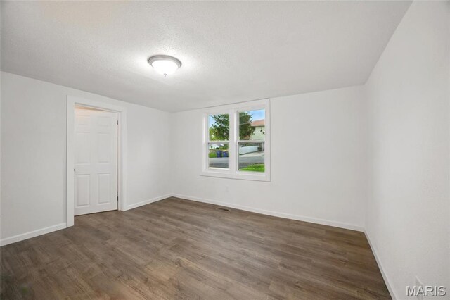 202 N Thomas St, De Soto, MO 63020 - spare room with wood finished floors, a textured ceiling, and baseboards