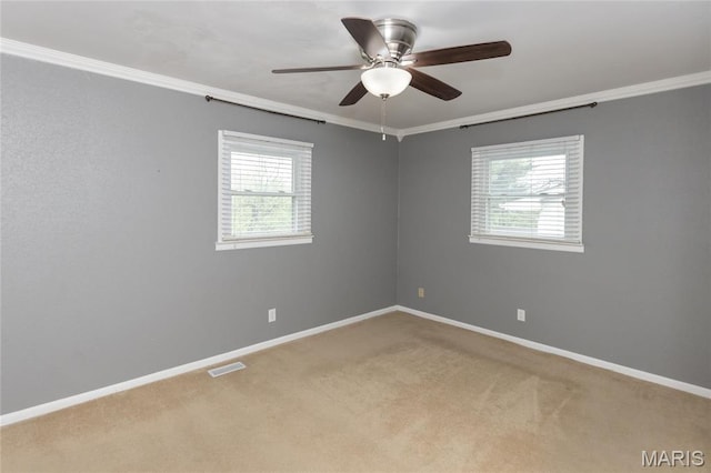 carpeted spare room featuring ornamental molding, a ceiling fan, and baseboards