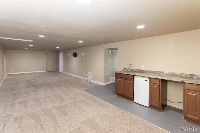 kitchen featuring fridge, recessed lighting, carpet floors, baseboards, and brown cabinetry
