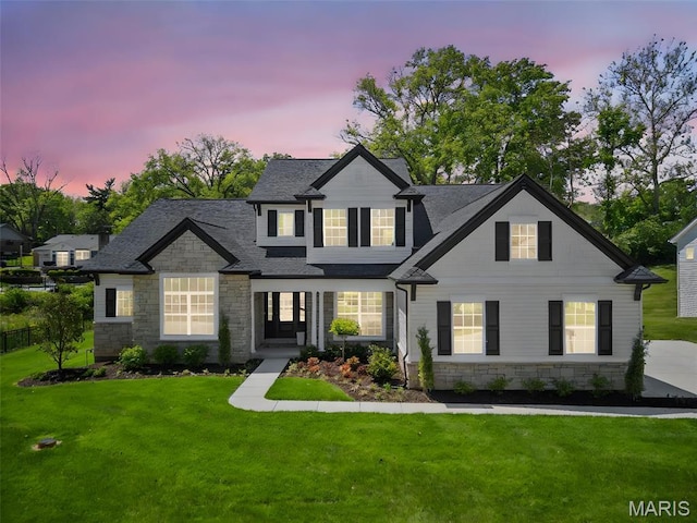 view of front of home featuring stone siding, a front yard, and roof with shingles