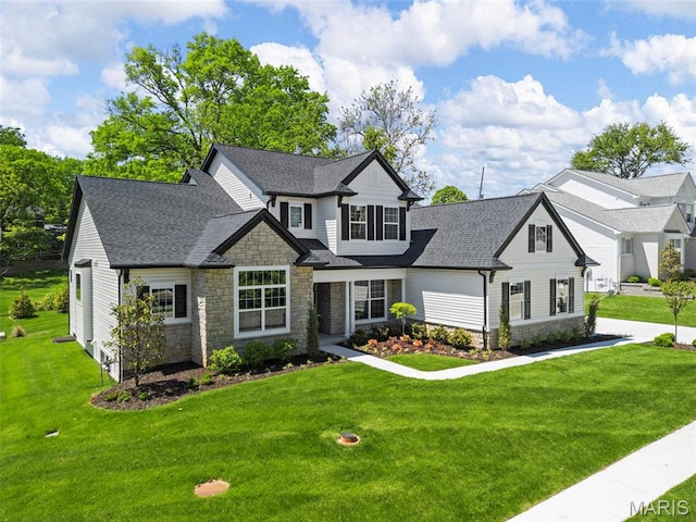 view of front of property with stone siding, roof with shingles, and a front lawn
