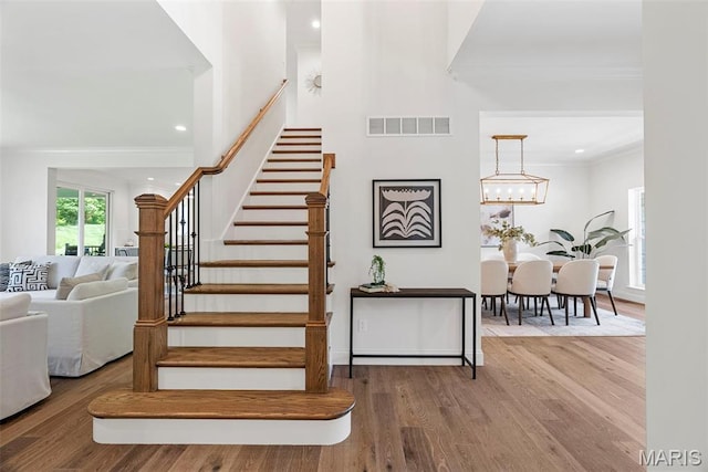 stairs featuring crown molding, wood finished floors, recessed lighting, a chandelier, and baseboards