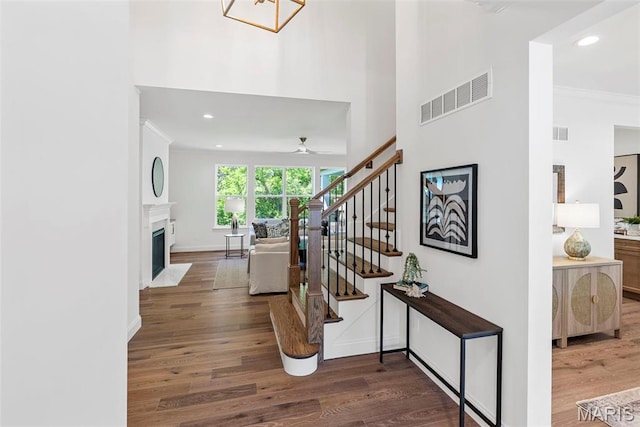 stairway featuring wood finished floors, ceiling fan, recessed lighting, a fireplace with flush hearth, and baseboards