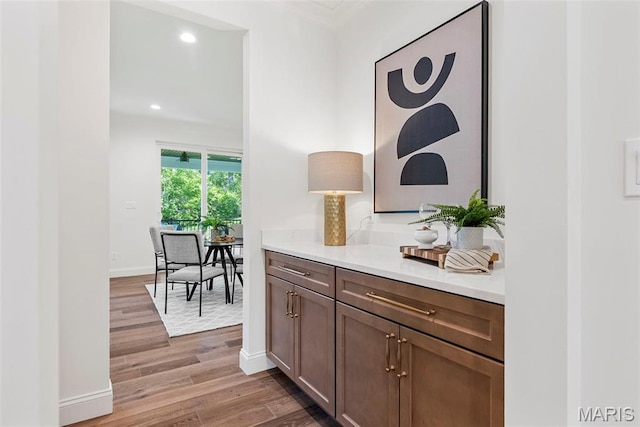 bar with wood finished floors, baseboards, recessed lighting, and ornamental molding