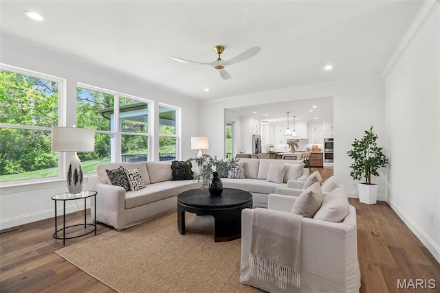 living area featuring healthy amount of natural light, ceiling fan, baseboards, ornamental molding, and recessed lighting