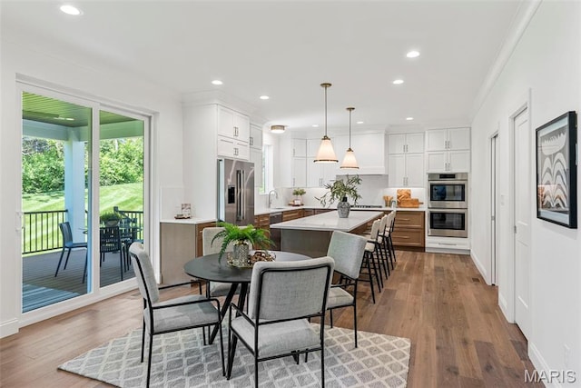 dining area with ornamental molding, recessed lighting, and wood finished floors